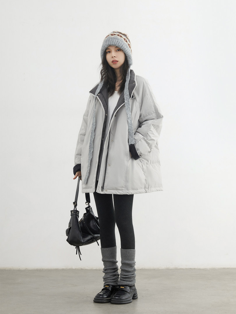 Model wearing a light gray oversized puffer coat with knit hat, leggings, and black bag and shoes