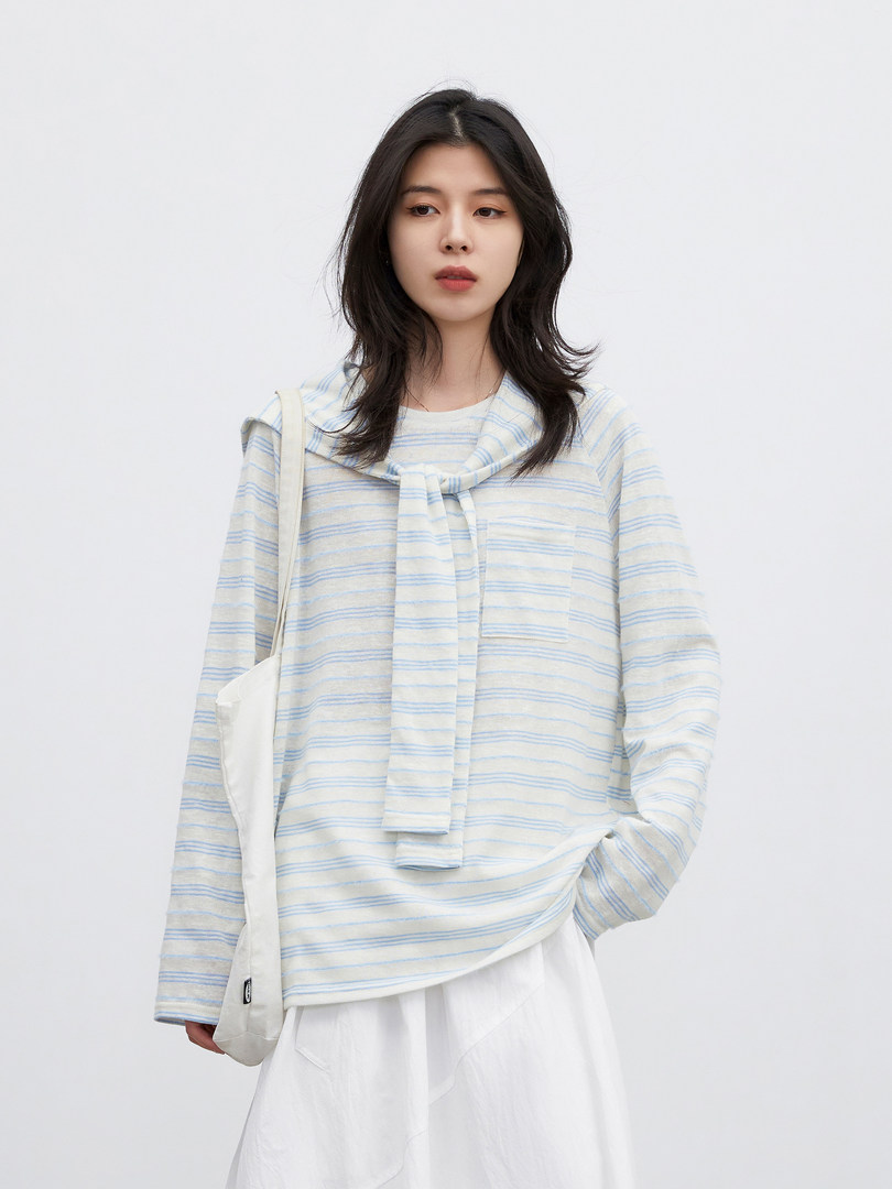 Model wearing a light striped long-sleeve top with a tie detail