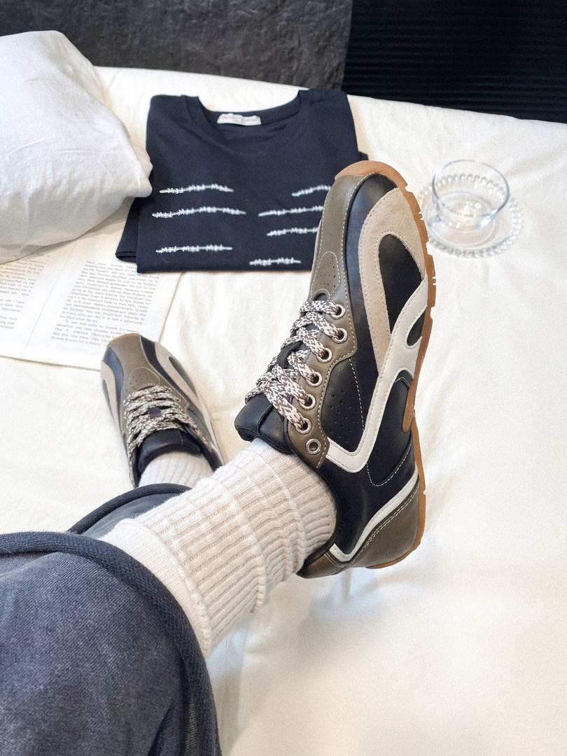 Casual lace-up sneakers worn with white socks on a seated model