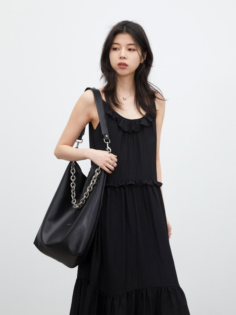 Black sleeveless ruffled midi dress with a large black shoulder bag on a model