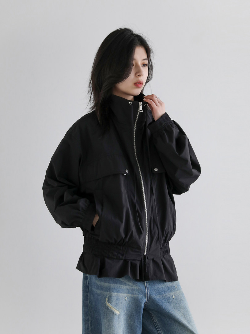 Black zip-up jacket worn by a model with blue jeans