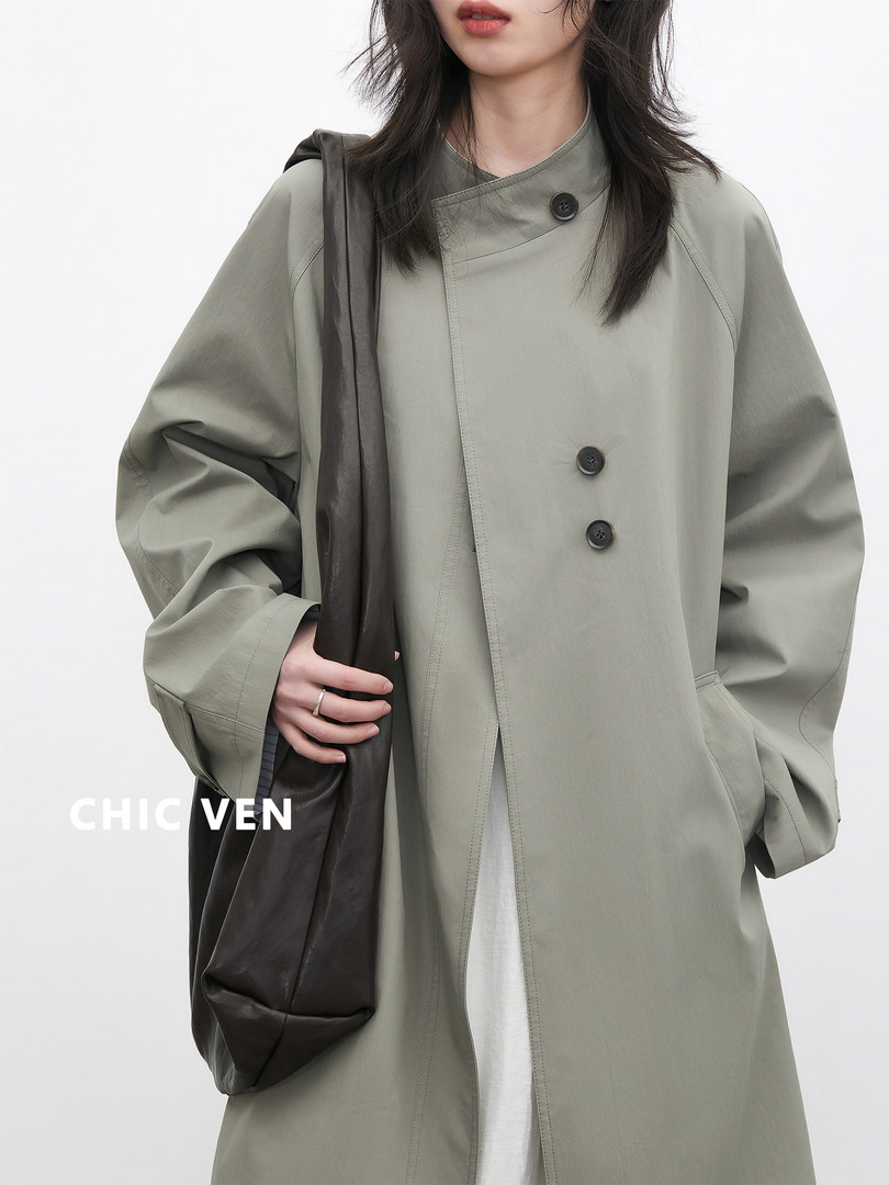 Model wearing a light gray oversized coat with black buttons and a dark shoulder bag