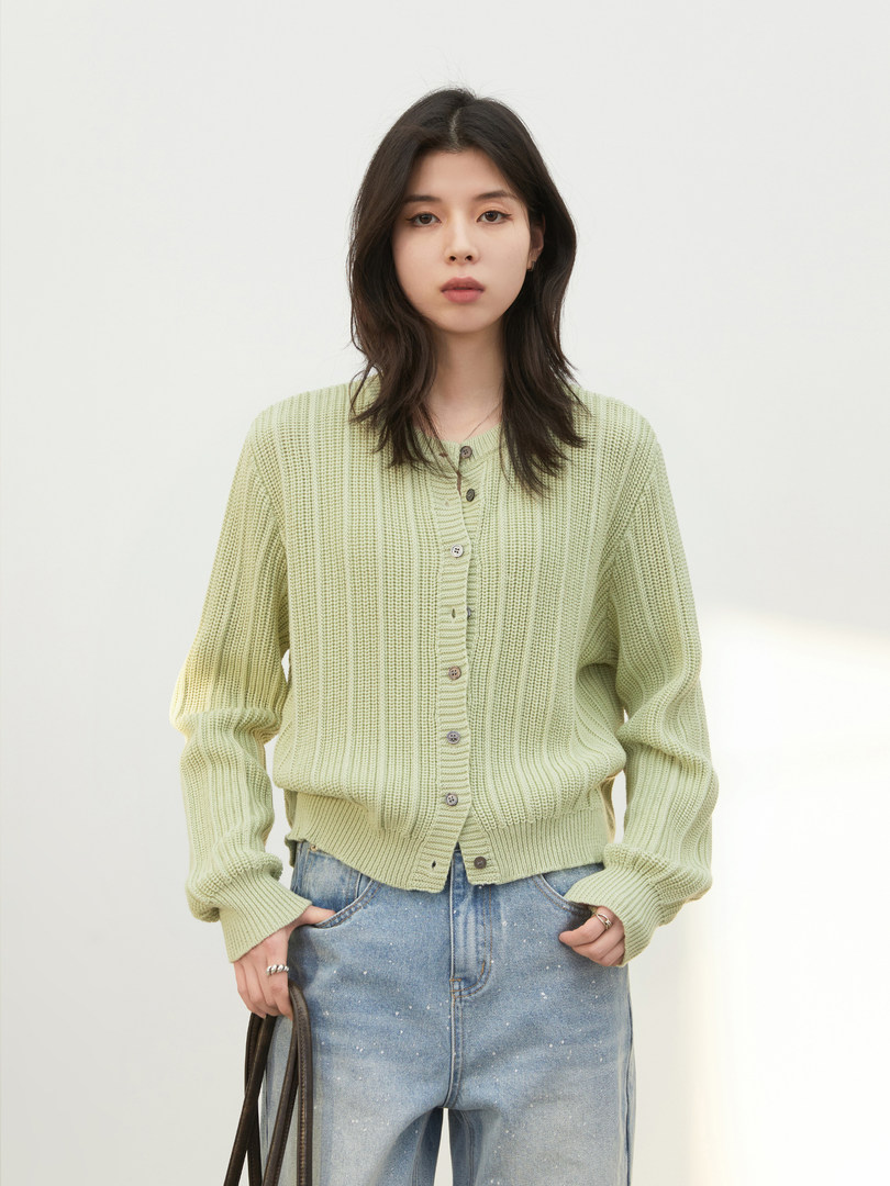 Model wearing a light green knit cardigan with jeans