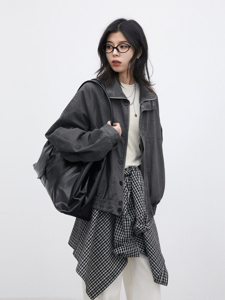 Model wearing a dark gray jacket layered over a checkered shirt and white top