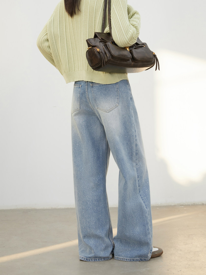 Person wearing a light knit sweater, wide-leg jeans, and a black leather shoulder bag