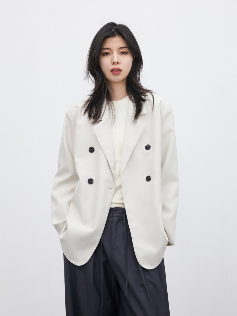Woman wearing a cream double-breasted blazer with dark trousers