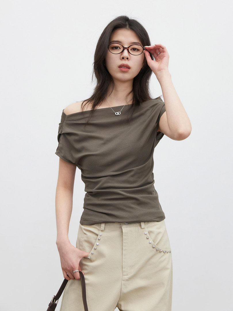 Model wearing an olive off-shoulder top with beige embellished pants