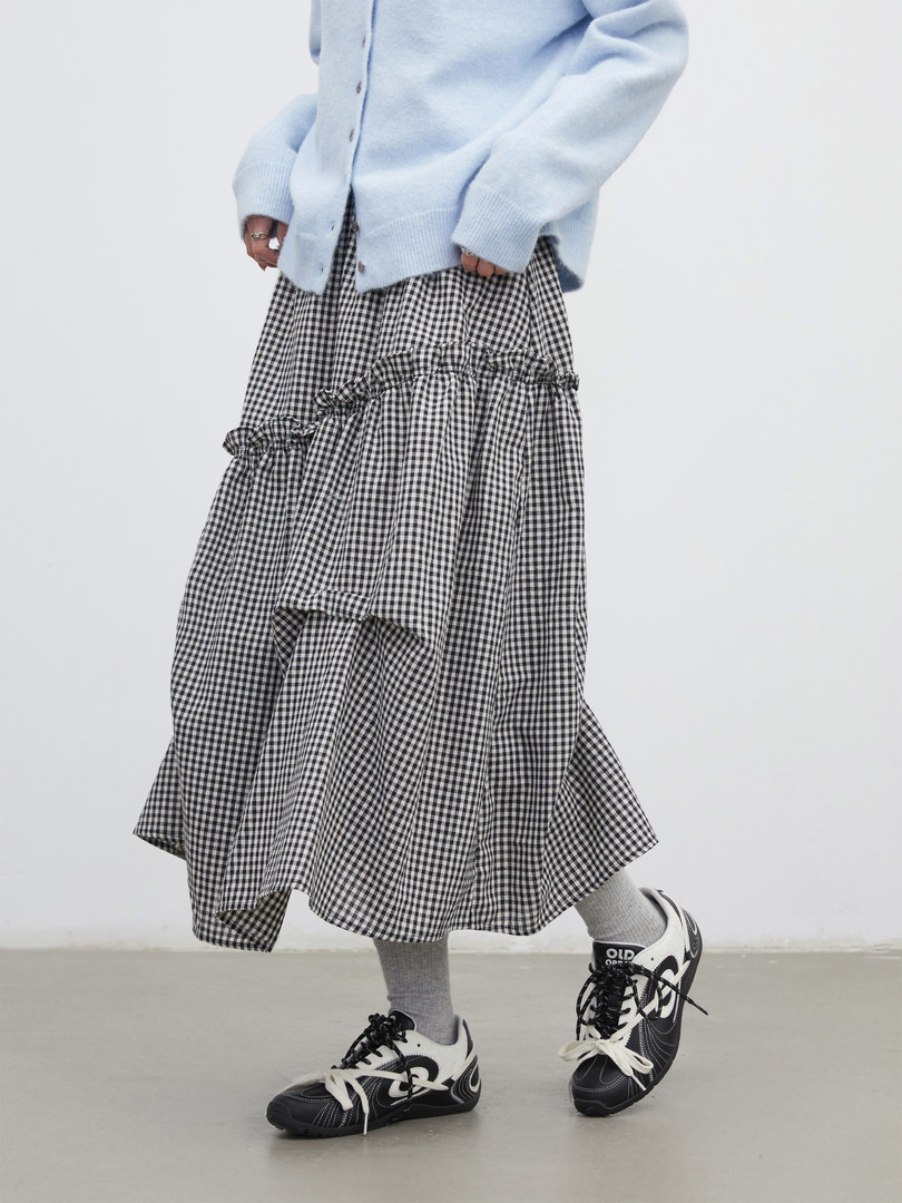 Model wearing a light blue cardigan with a black-and-white gingham skirt and sneakers