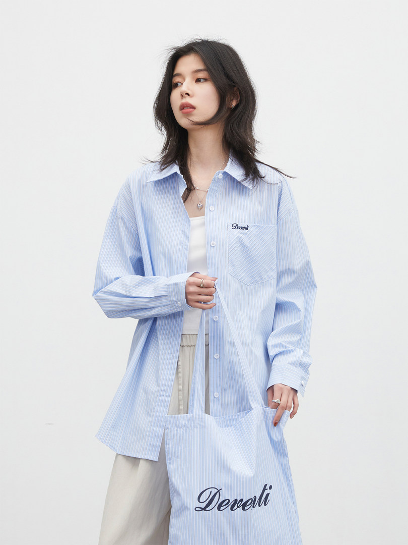 Model wearing a light blue striped oversized button-up shirt
