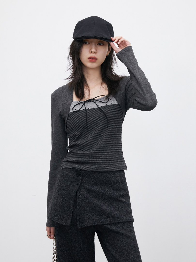 Model wearing a dark layered long-sleeve outfit with a black cap