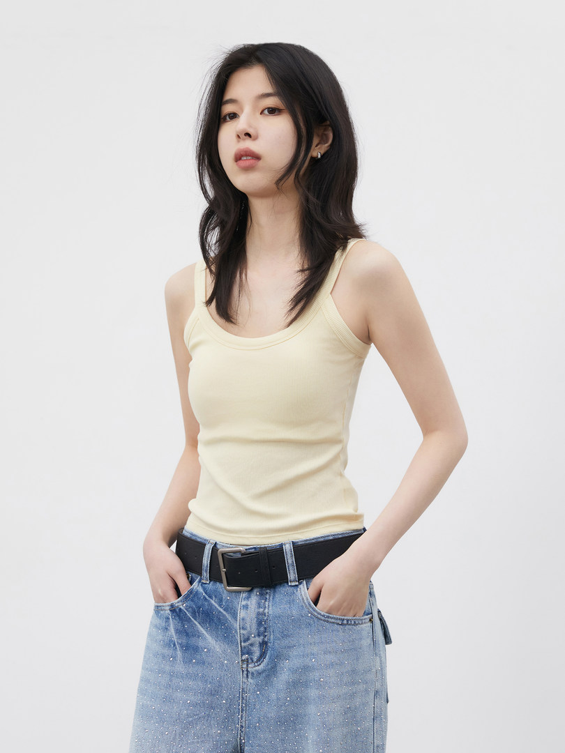 Model wearing a light yellow ribbed tank top with a blue denim skirt and black belt