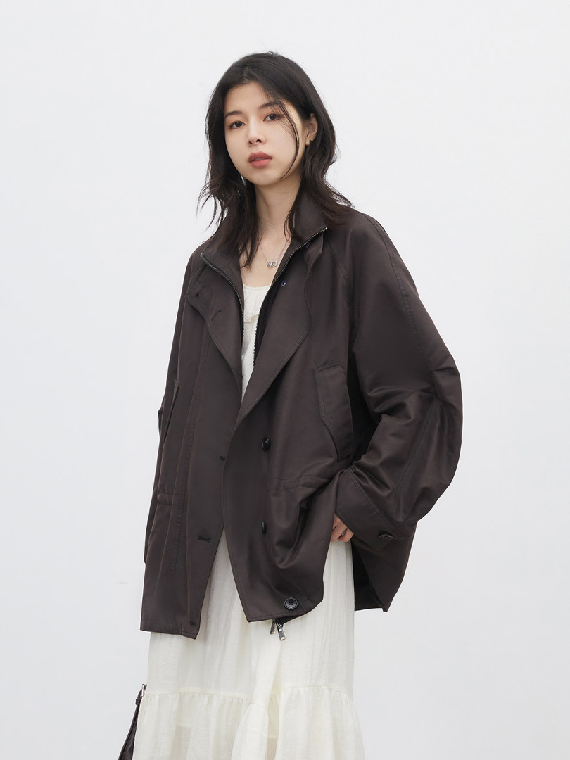 Model wearing a dark oversized jacket over a light dress