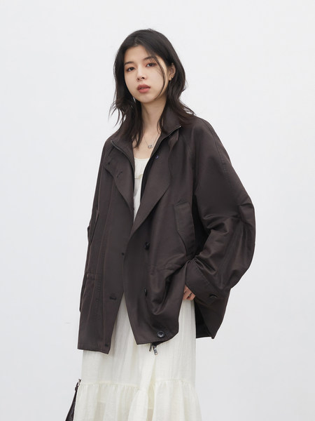 Model wearing a dark oversized jacket over a light dress
