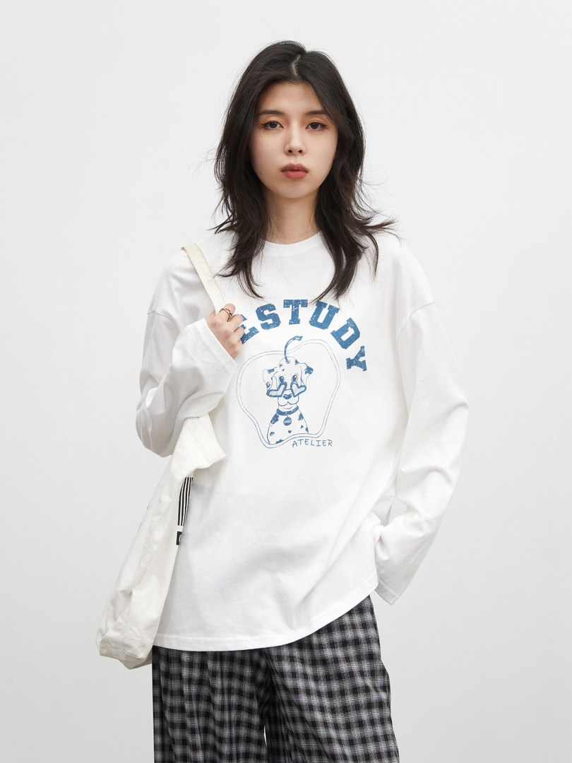 Model wearing a white graphic long-sleeve shirt with blue text and illustration