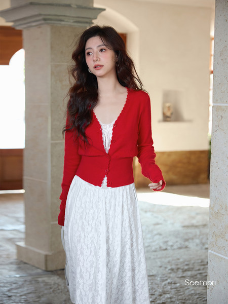 Model wearing a red cardigan over a white lace dress
