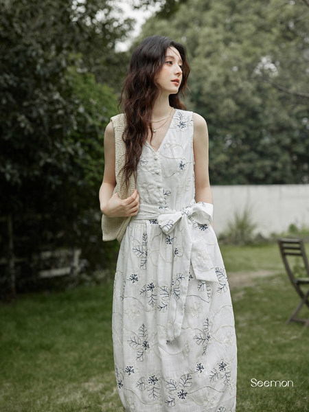 Woman wearing a white sleeveless floral dress outdoors
