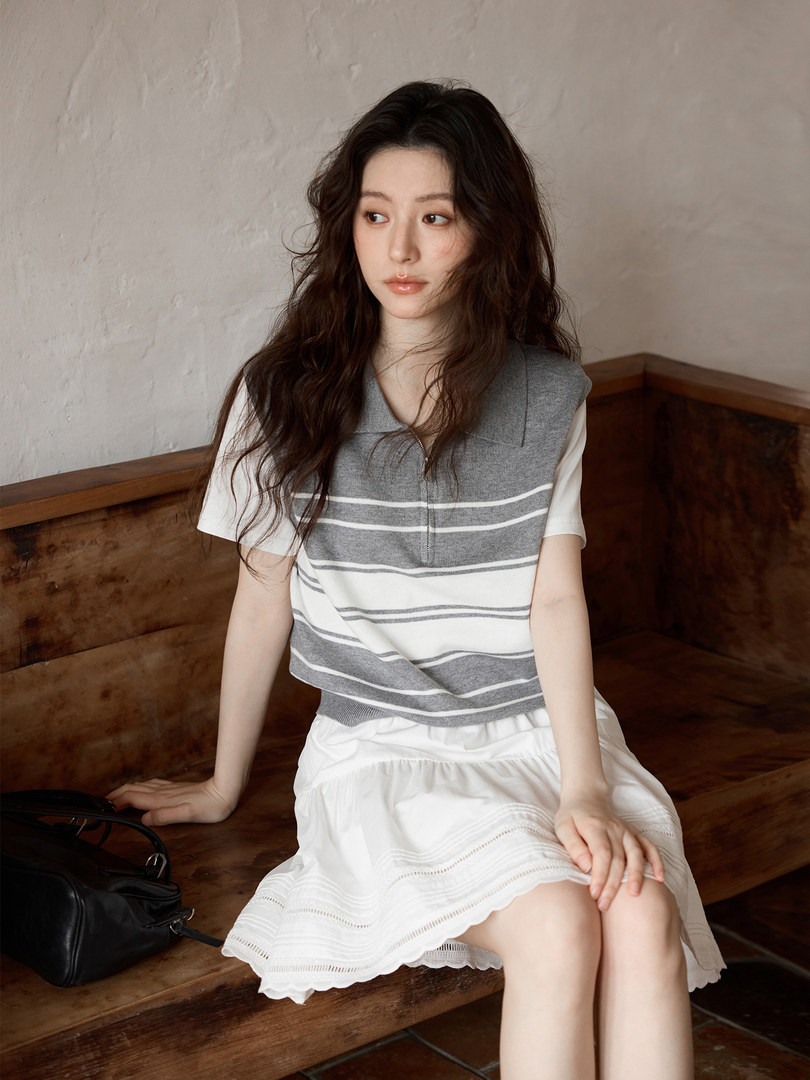 Model wearing a gray striped sleeveless knit top with a white skirt