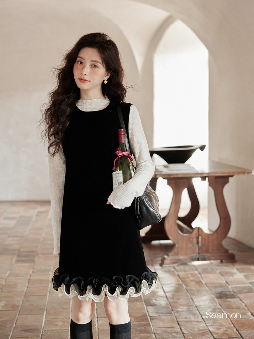 Black sleeveless ruffle-hem dress worn over a white long-sleeve top