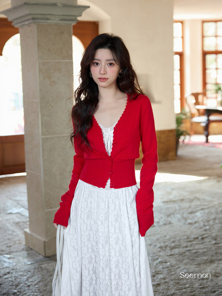 Woman wearing a red buttoned cardigan over a white lace dress