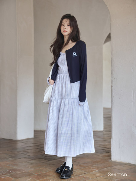 Model wearing a light plaid dress with a navy cardigan and loafers