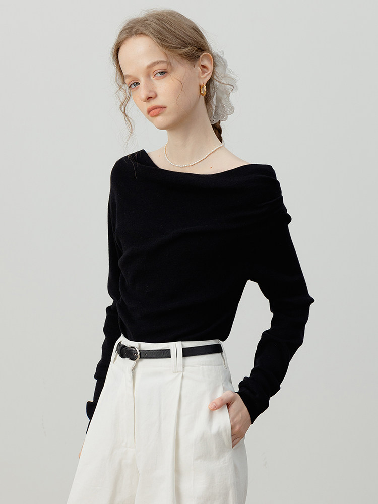 Model wearing a black off-shoulder long-sleeve top with white pants