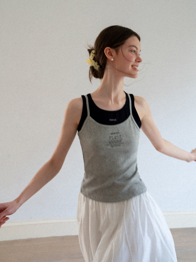 Woman wearing a gray sleeveless tank top over a black base layer