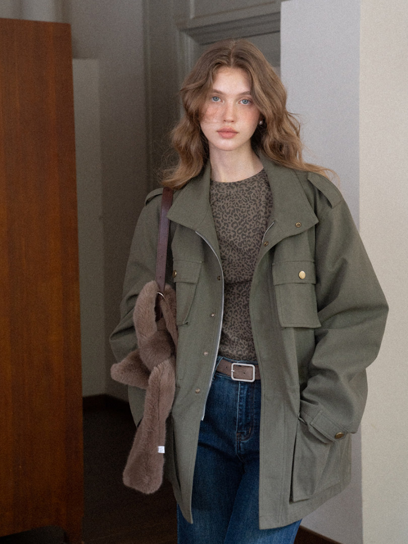 Olive green utility jacket worn by a model with jeans and a printed top