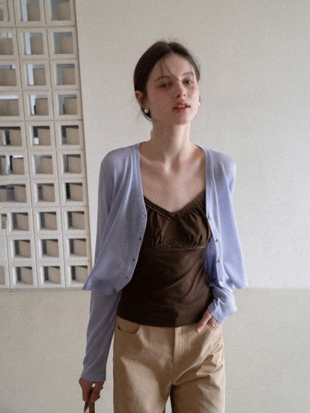 Model wearing a light blue cardigan over a brown camisole with beige pants