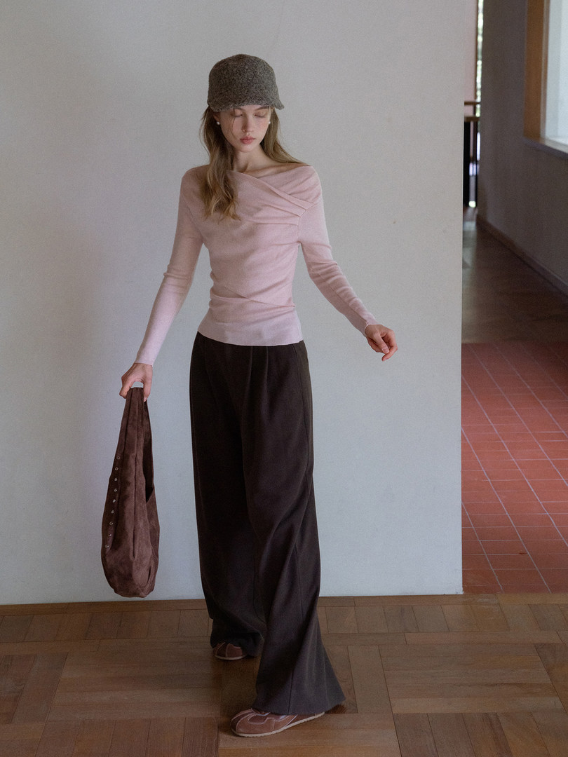 Model wearing a pale pink long-sleeve top with black wide-leg pants and a brown handbag