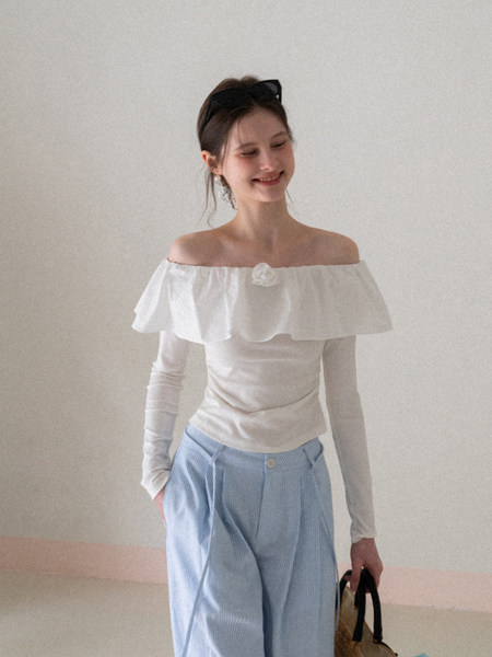 Woman wearing a white off-shoulder top with light blue pleated pants
