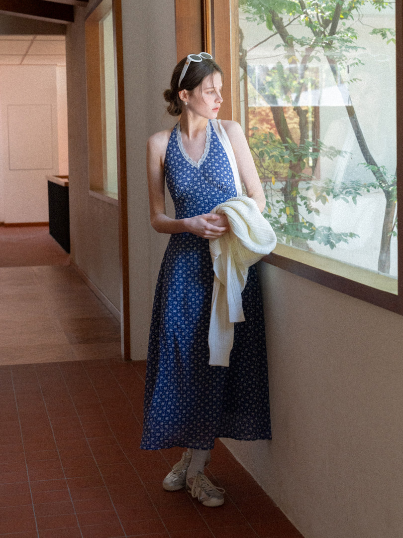Woman wearing a blue floral halter dress in a hallway