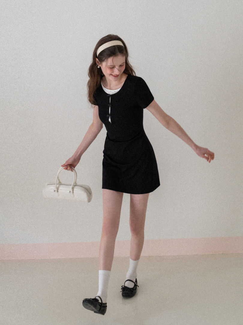 Black short-sleeve mini dress worn by a model with white accessories