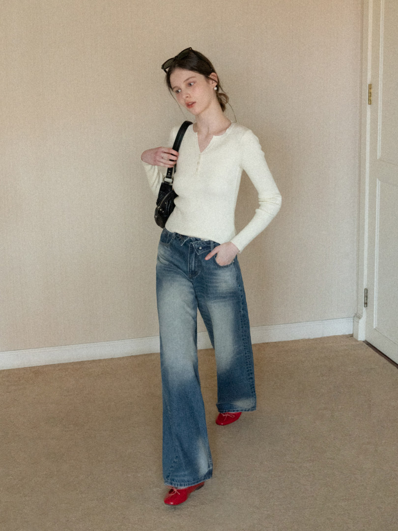 Woman wearing a cream long-sleeve top with wide-leg blue jeans and red shoes