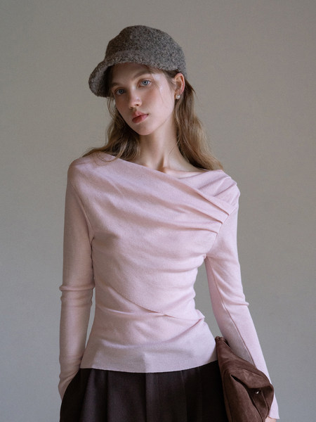 Model wearing a pale pink draped long-sleeve top with a gray cap