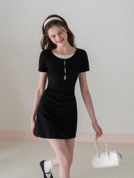 Black short-sleeve mini dress worn by a model with a white handbag