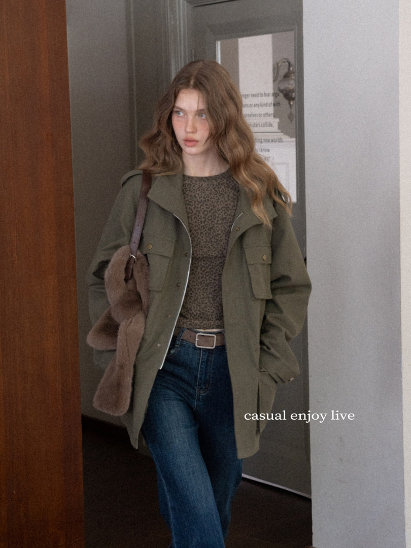 Woman wearing an olive jacket, leopard top, jeans, and a brown shoulder bag