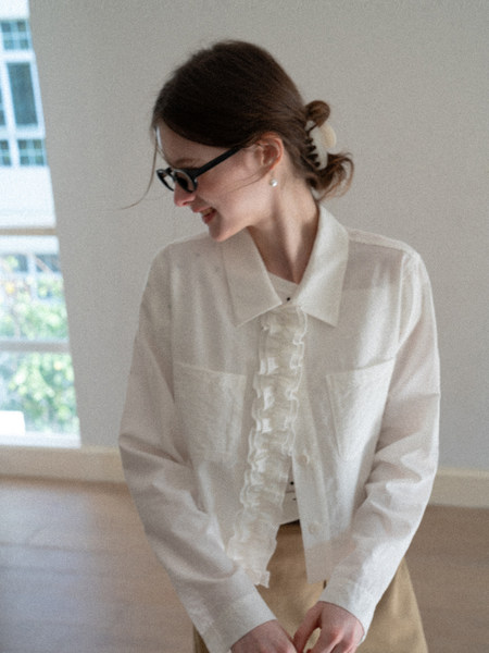 Woman wearing a sheer white blouse with a large collar and long sleeves