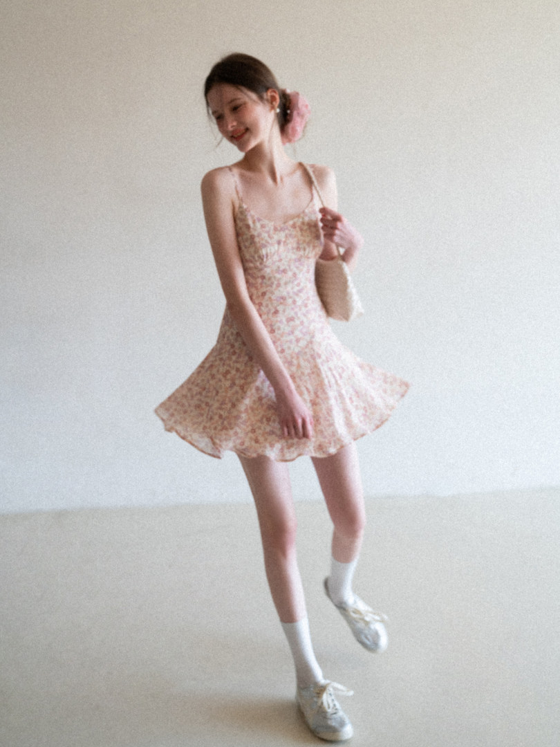 Model wearing a floral sleeveless mini dress with white sneakers
