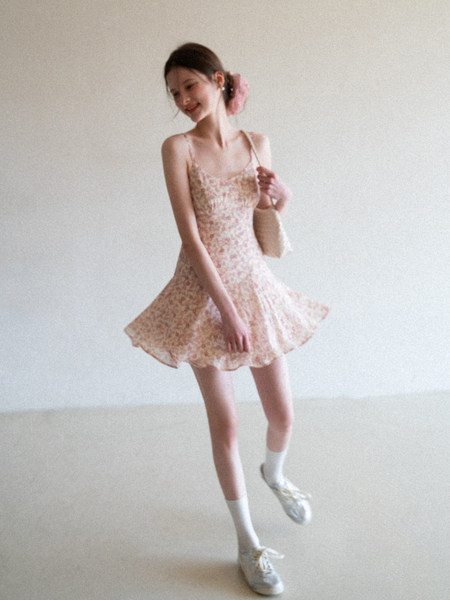 Model wearing a floral sleeveless mini dress with white sneakers