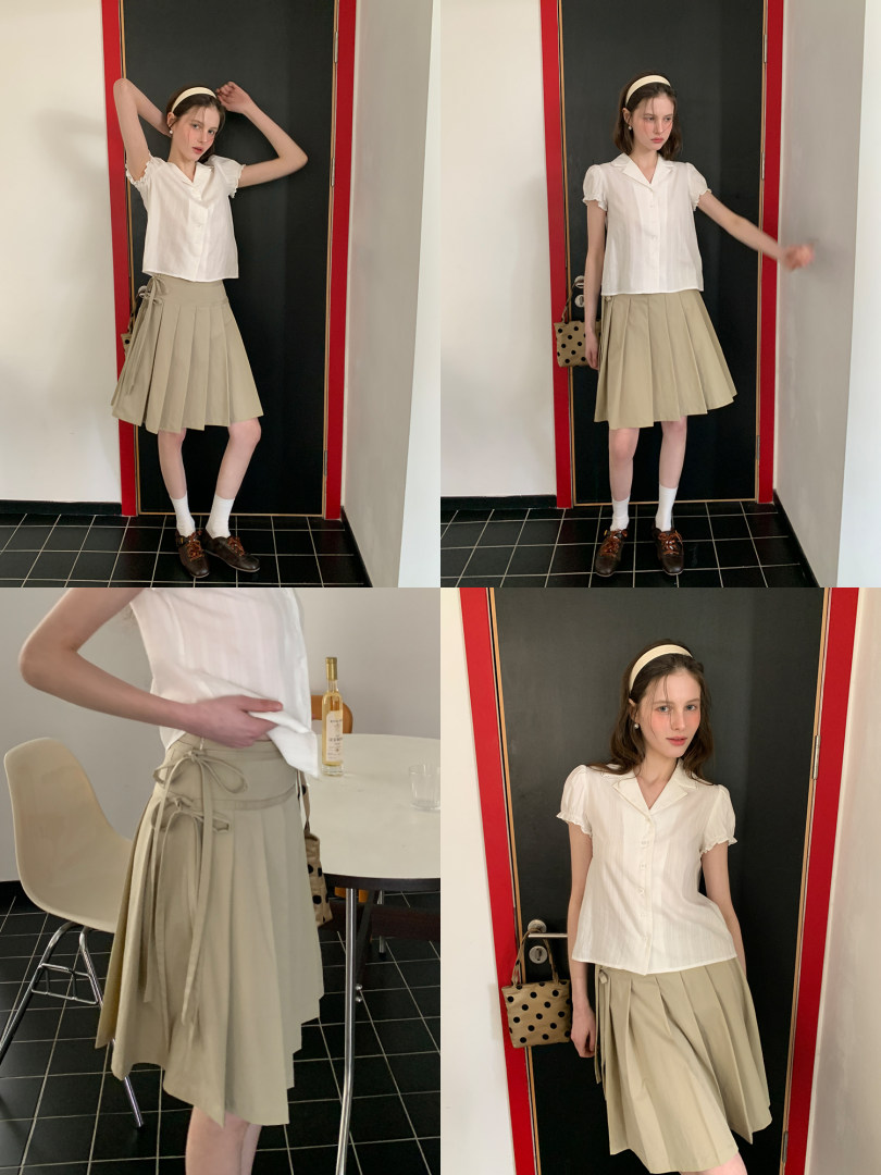Model wearing a white short-sleeve blouse with a beige pleated skirt