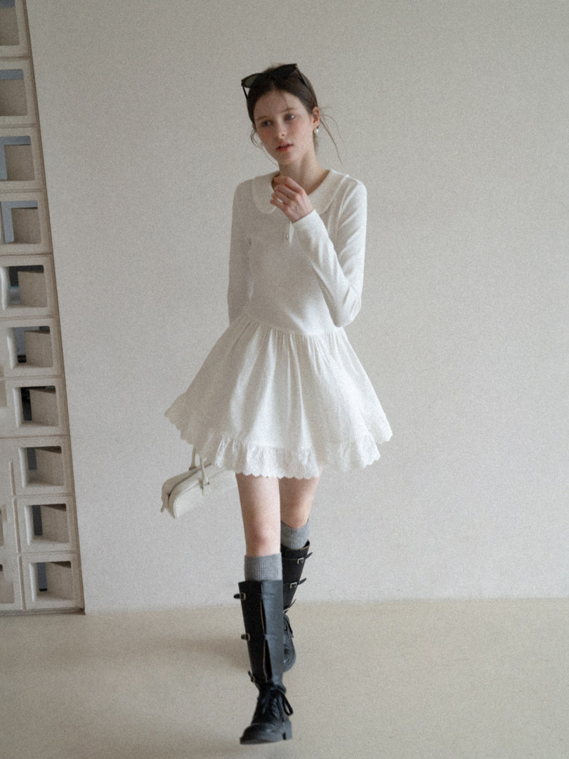 Woman modeling a white long-sleeve dress with a ruffled skirt and black boots