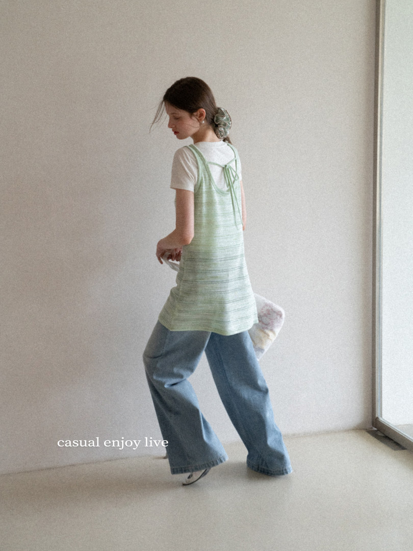 Model wearing a mint green sleeveless top over a white tee with wide-leg jeans.