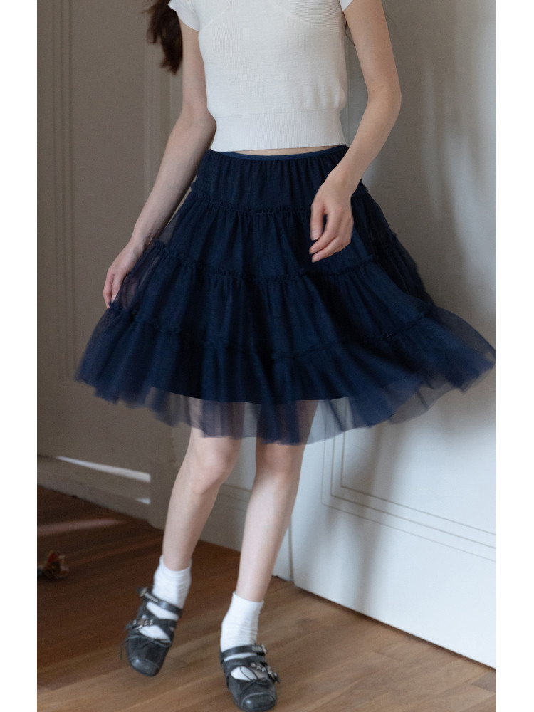Model wearing a navy layered tulle skirt with a white crop top