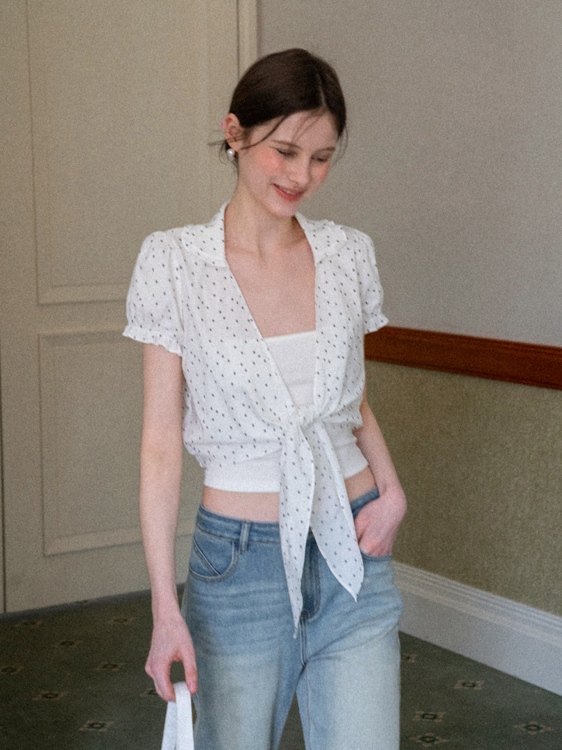 Woman wearing a white patterned tie-front blouse with jeans