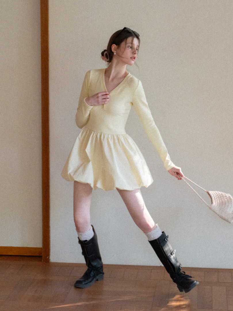 Model wearing a pale yellow long-sleeve mini dress with a flared skirt