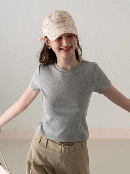 Woman wearing a gray fitted t-shirt with a beige printed cap and beige pants