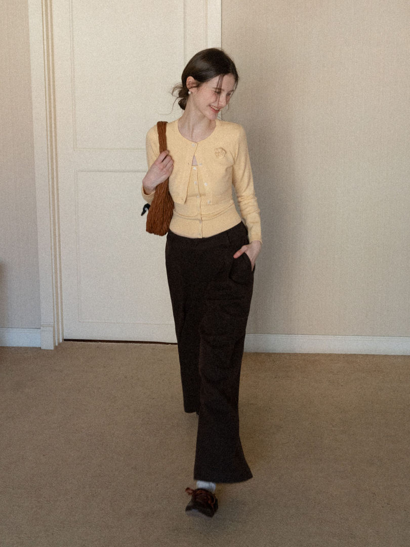 Woman modeling a pale yellow cardigan with black wide-leg pants and a brown shoulder bag