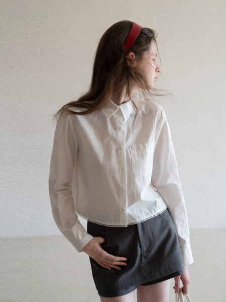 Model wearing a white button-up blouse and black shorts