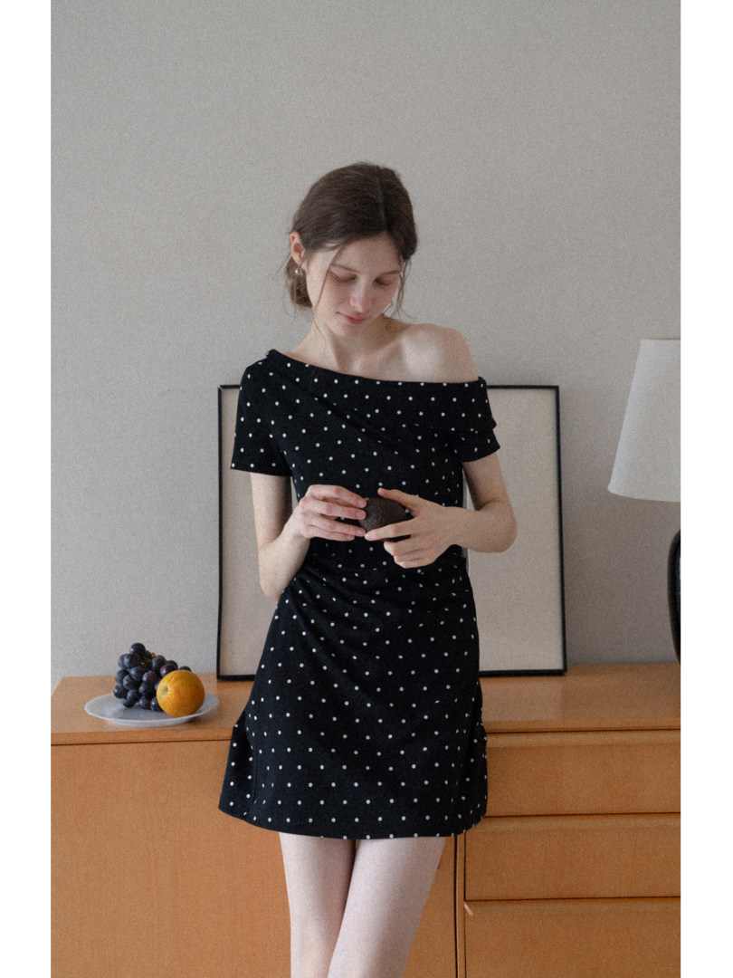 Woman wearing a black off-shoulder polka dot mini dress