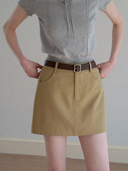 Model wearing a tan belted skirt with a gray top